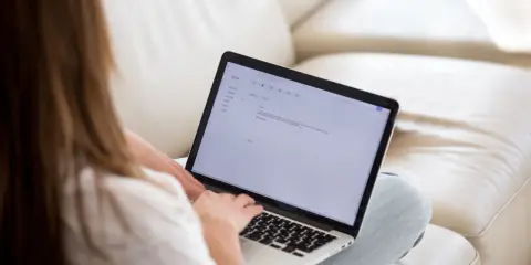 Kobieta pisze maila na laptopie, podkreślając ważne fragmenty tekstu.