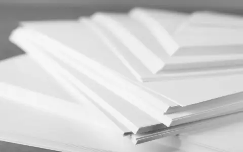 Stosy białego papieru offsetowego ułożone warstwowo, tworząc geometryczne kształty.