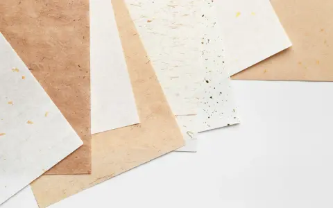 Różne rodzaje papieru, od gładkich po z widocznymi włóknami i złotymi płatkami.